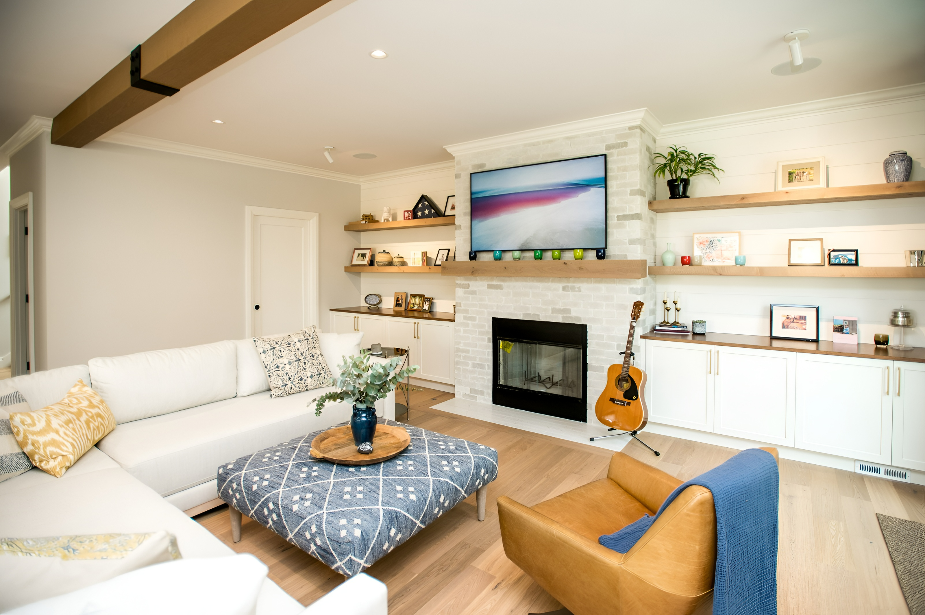 Cozy family room with whitewashed brick fireplace, floating oak shelves and white sectional